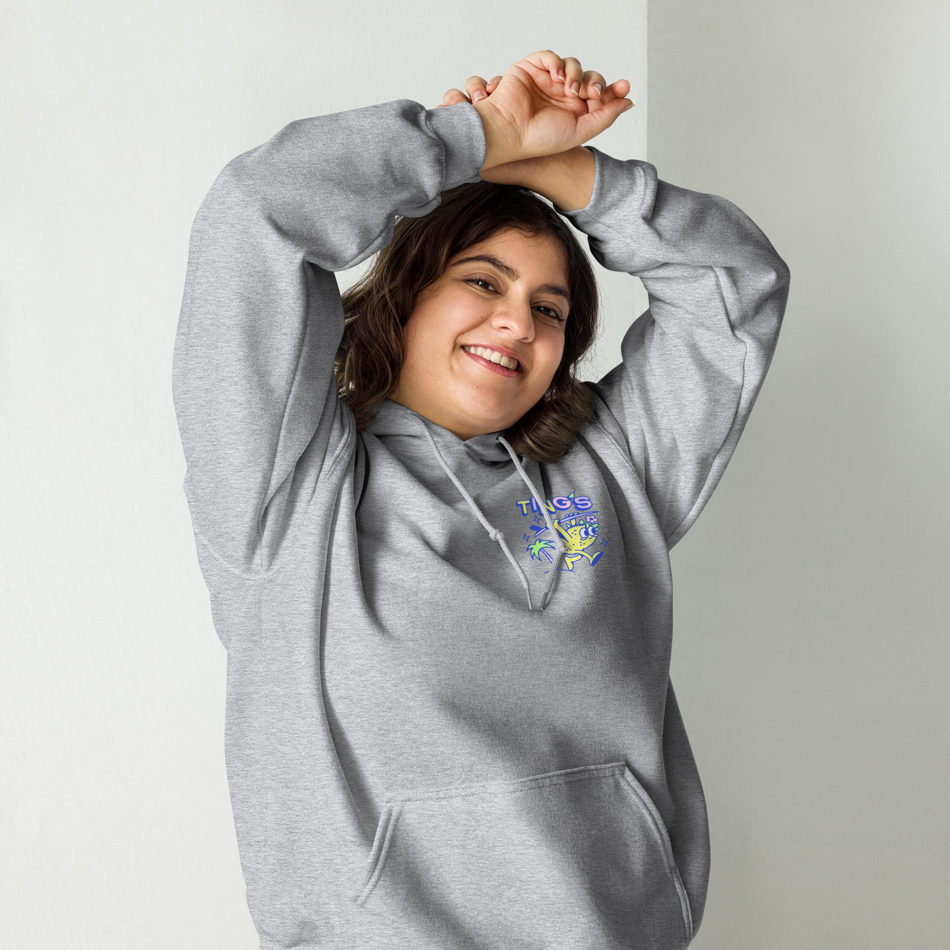 Female model wearing Ting's heather grey unisex hoodie with Ting's logo on front